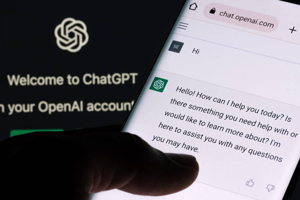 ChatGPT chatbot screen seen on smartphone and laptop display with Chat GPT login screen on the background.